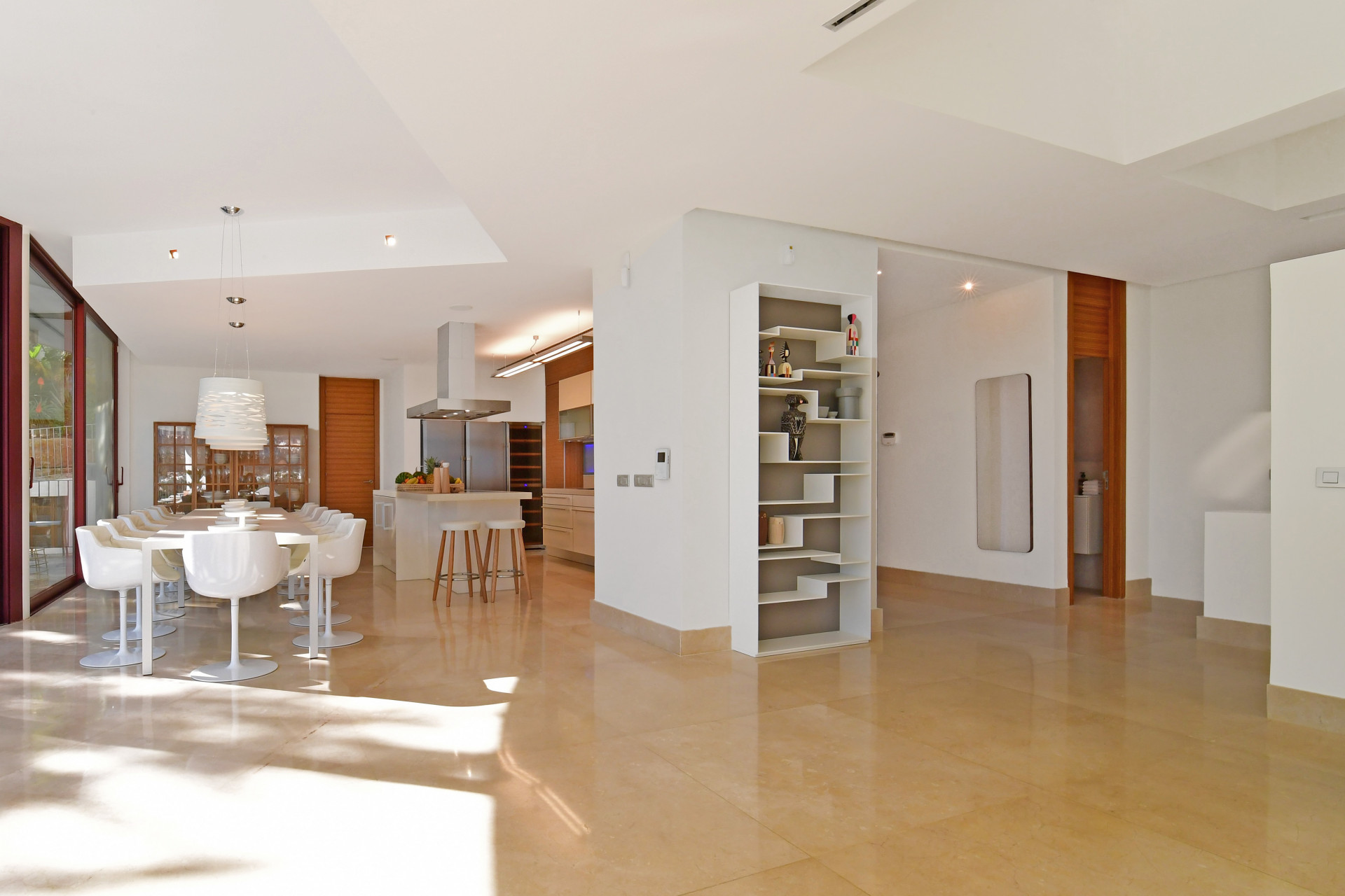 Dining space adjacent to kitchen, with white chairs and a contemporary design