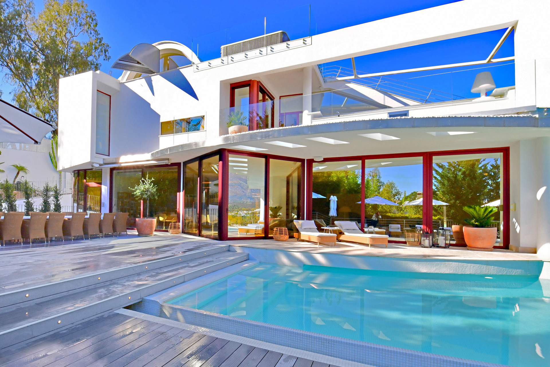 Exterior view highlighting the pool and the house's modern design with surrounding greenery.
