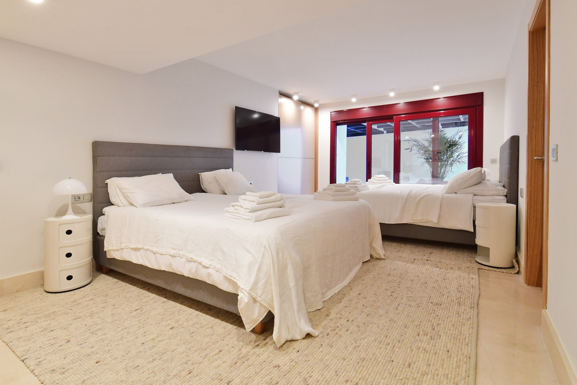 Double bedroom with two beds, a TV, and large glass doors leading outdoors