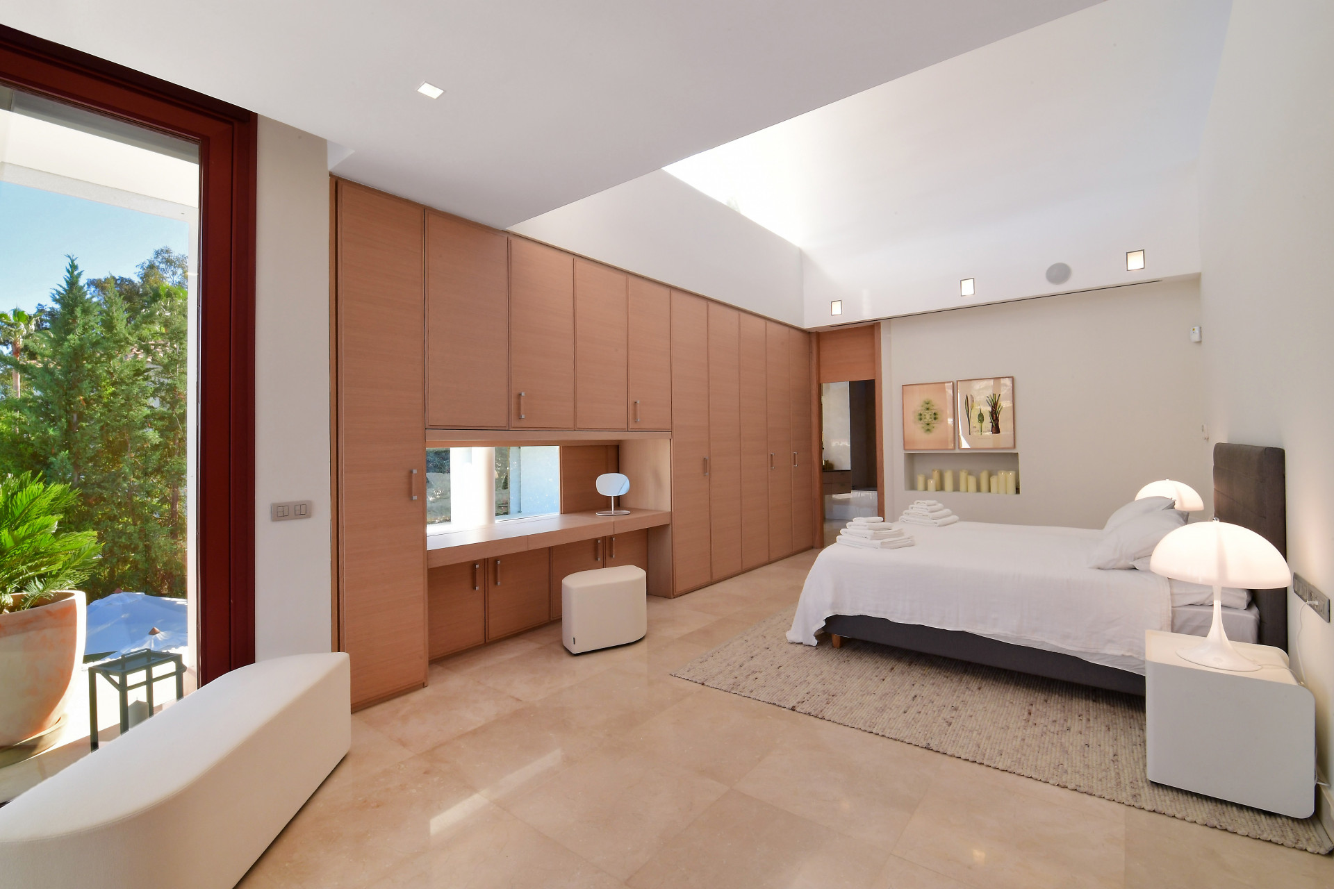 Master bedroom featuring built-in wardrobes, large window, and neutral decor with a cozy ambiance.