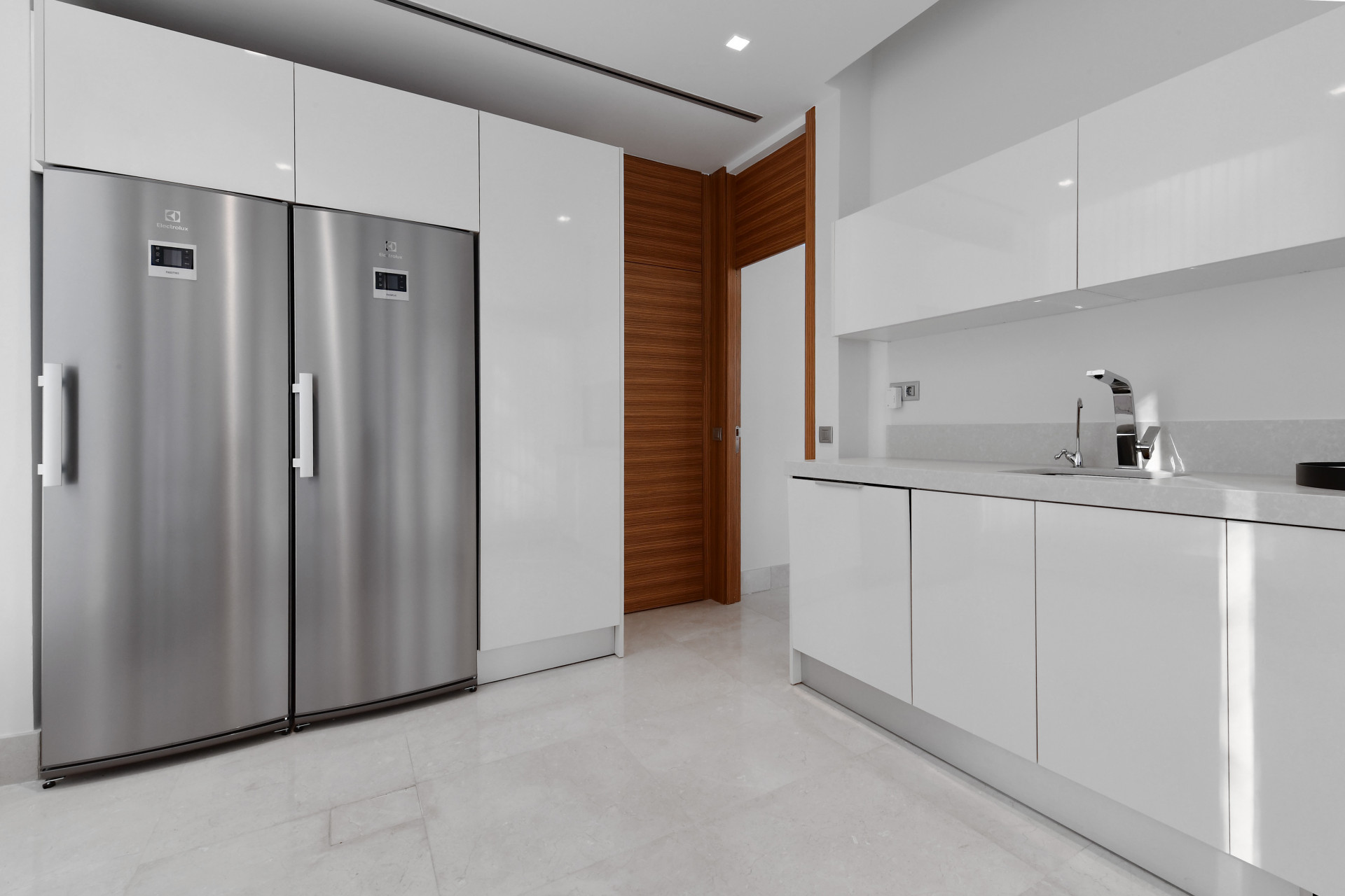 Sleek modern kitchen with stainless steel appliances and glossy white cabinetry.