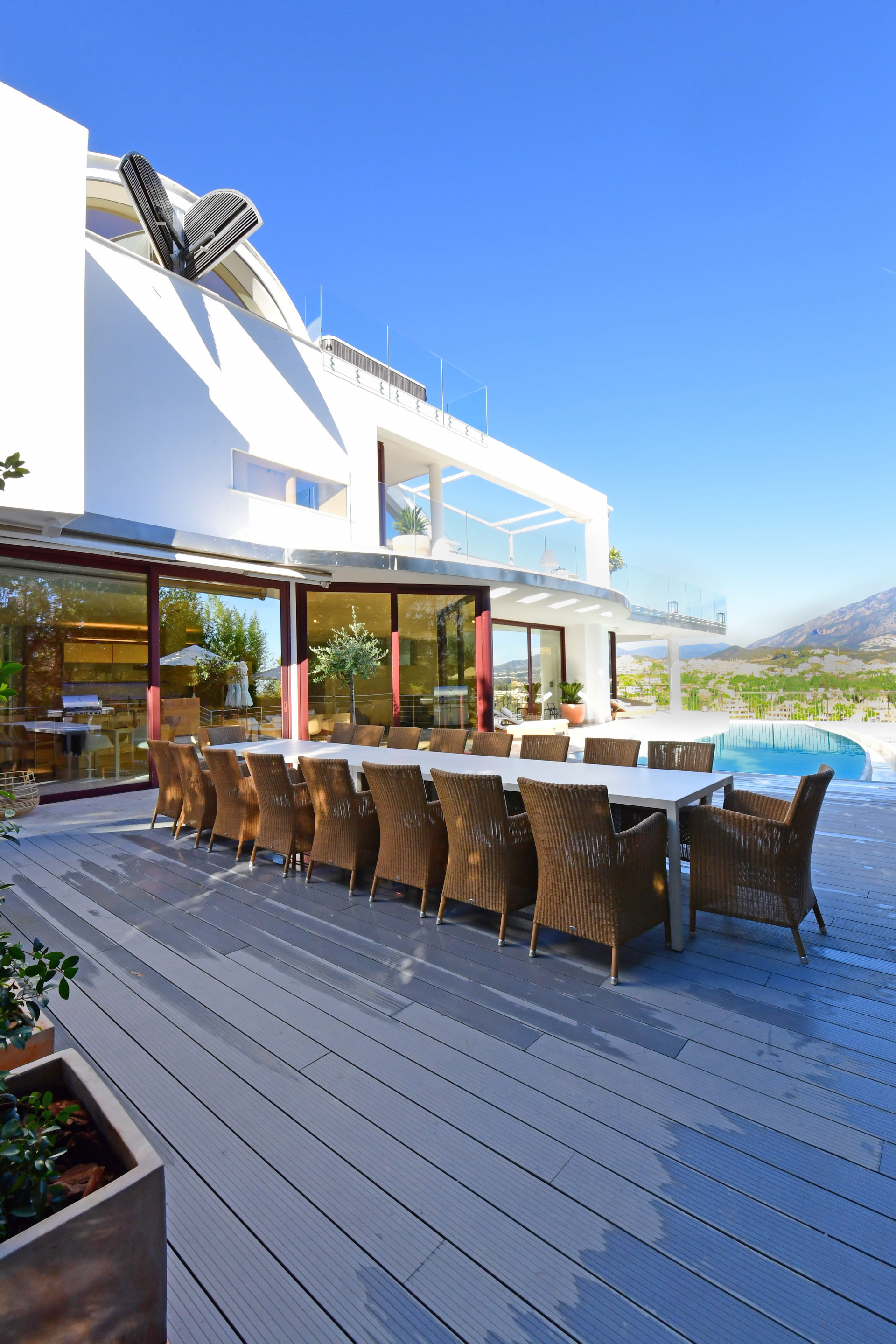 Large dining table on a wooden deck, with views of the pool and landscape.