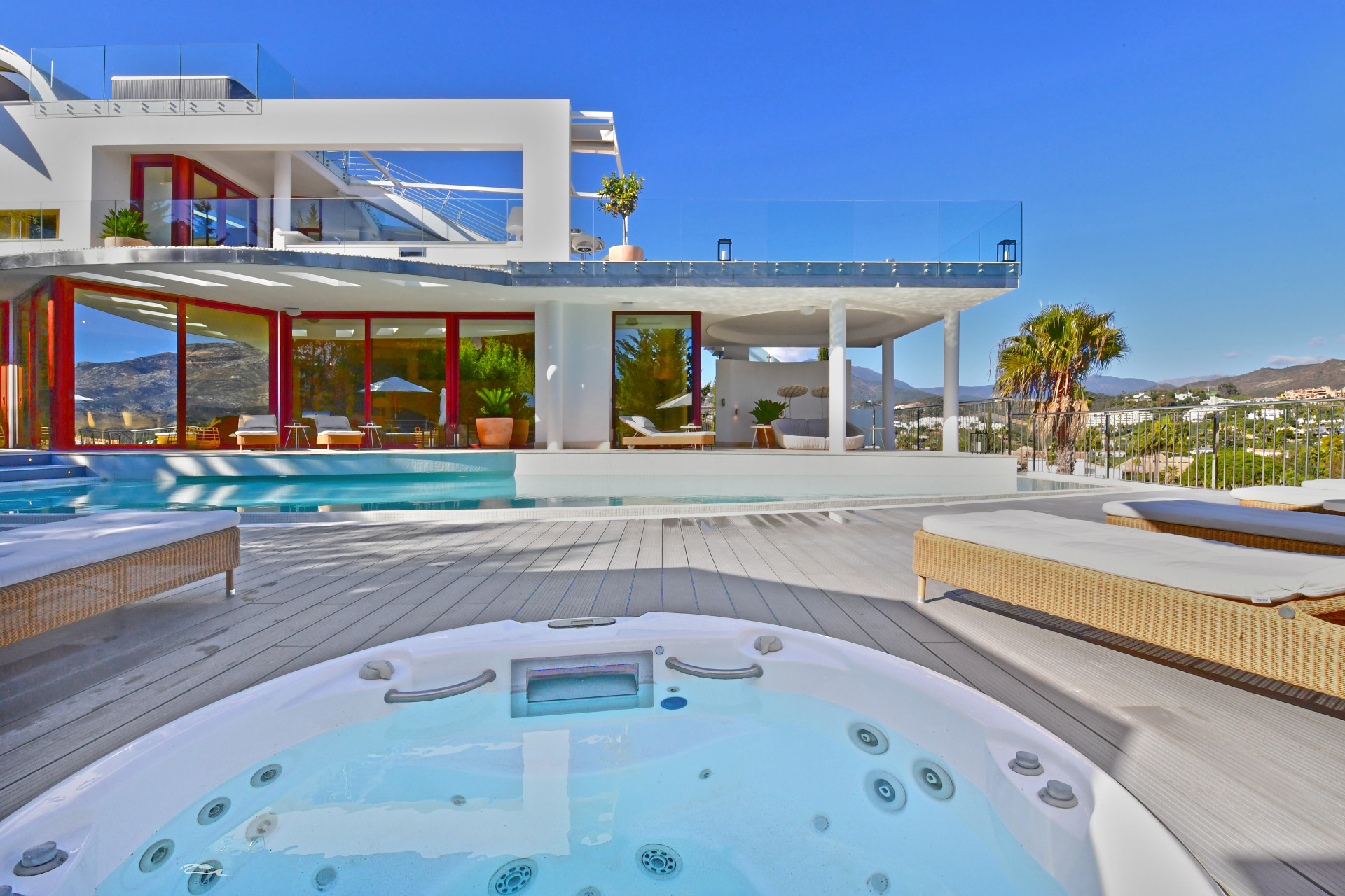 Outdoor jacuzzi with a view of the pool and surrounding hills.