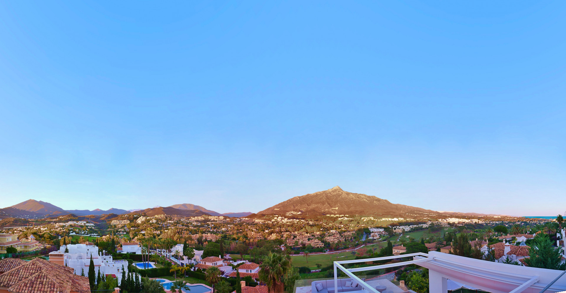 Panoramic view from the rooftop capturing the mountains and villas in the valley below.
