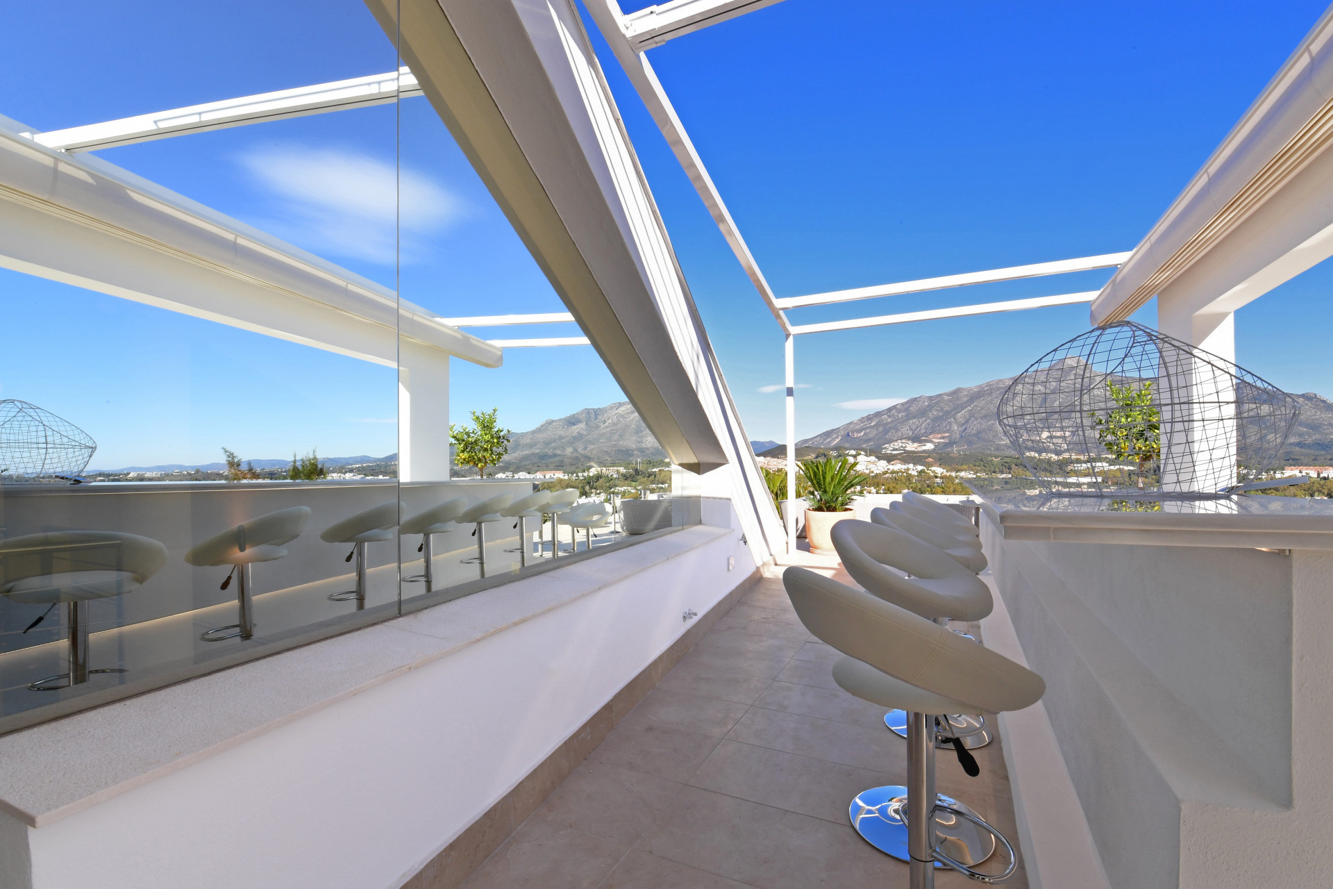 Outdoor bar area with modern stools and mountain views