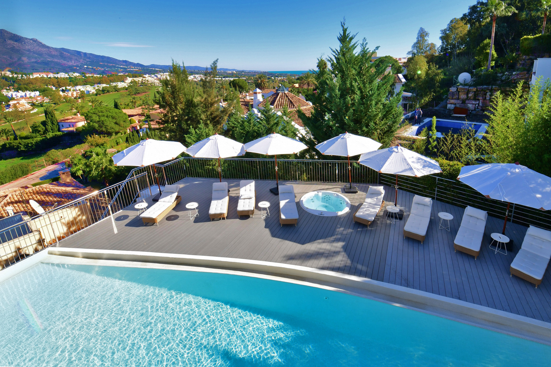 Outdoor terrace with sun loungers, umbrellas, and views of the surrounding landscape.