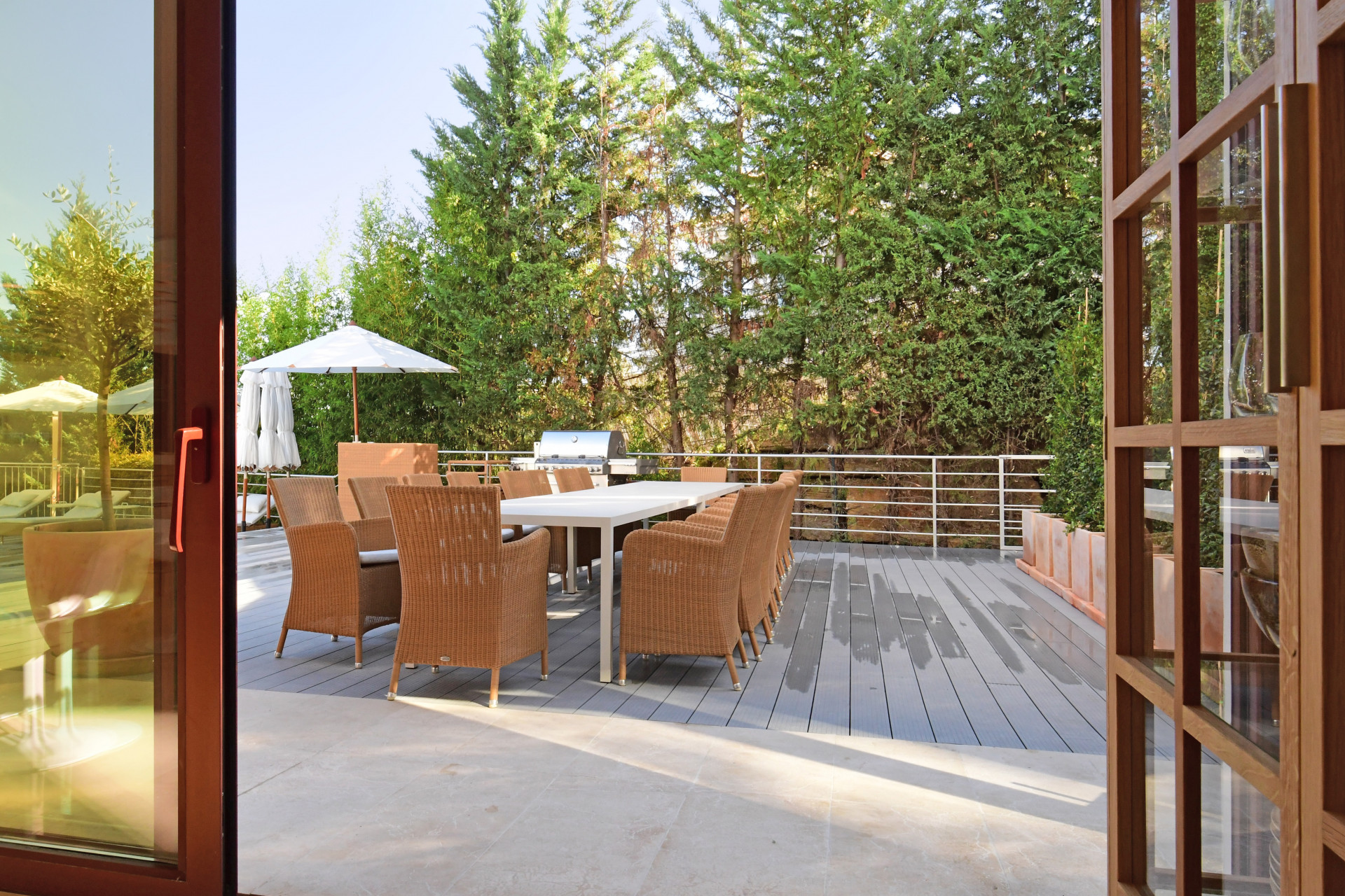 Patio view showing a dining table and chairs with green foliage in the background.