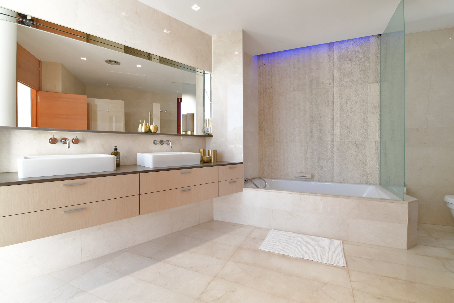Spacious bathroom featuring double sinks, wooden cabinetry, and a glass shower enclosure.