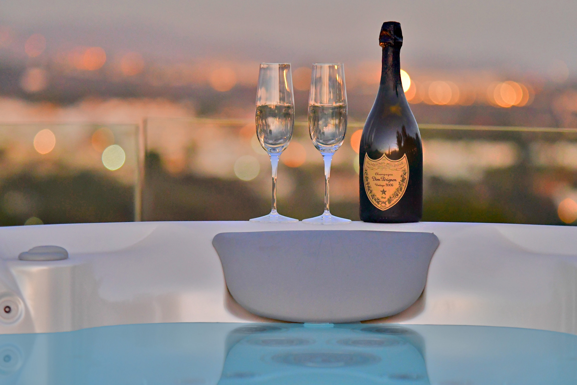 Champagne and glasses on the edge of a hot tub at sunset
