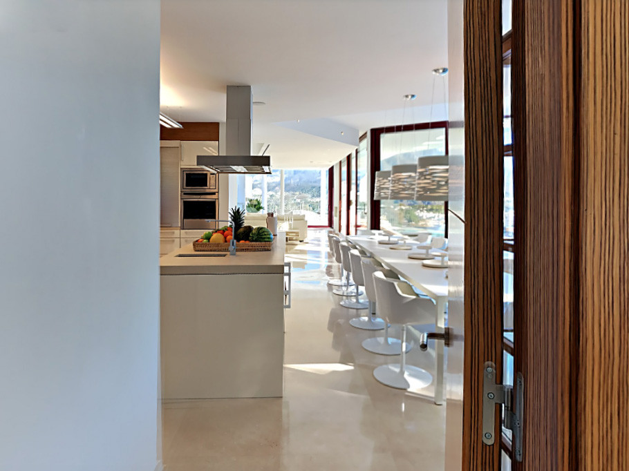 Modern kitchen with an island and dining area, featuring large windows.