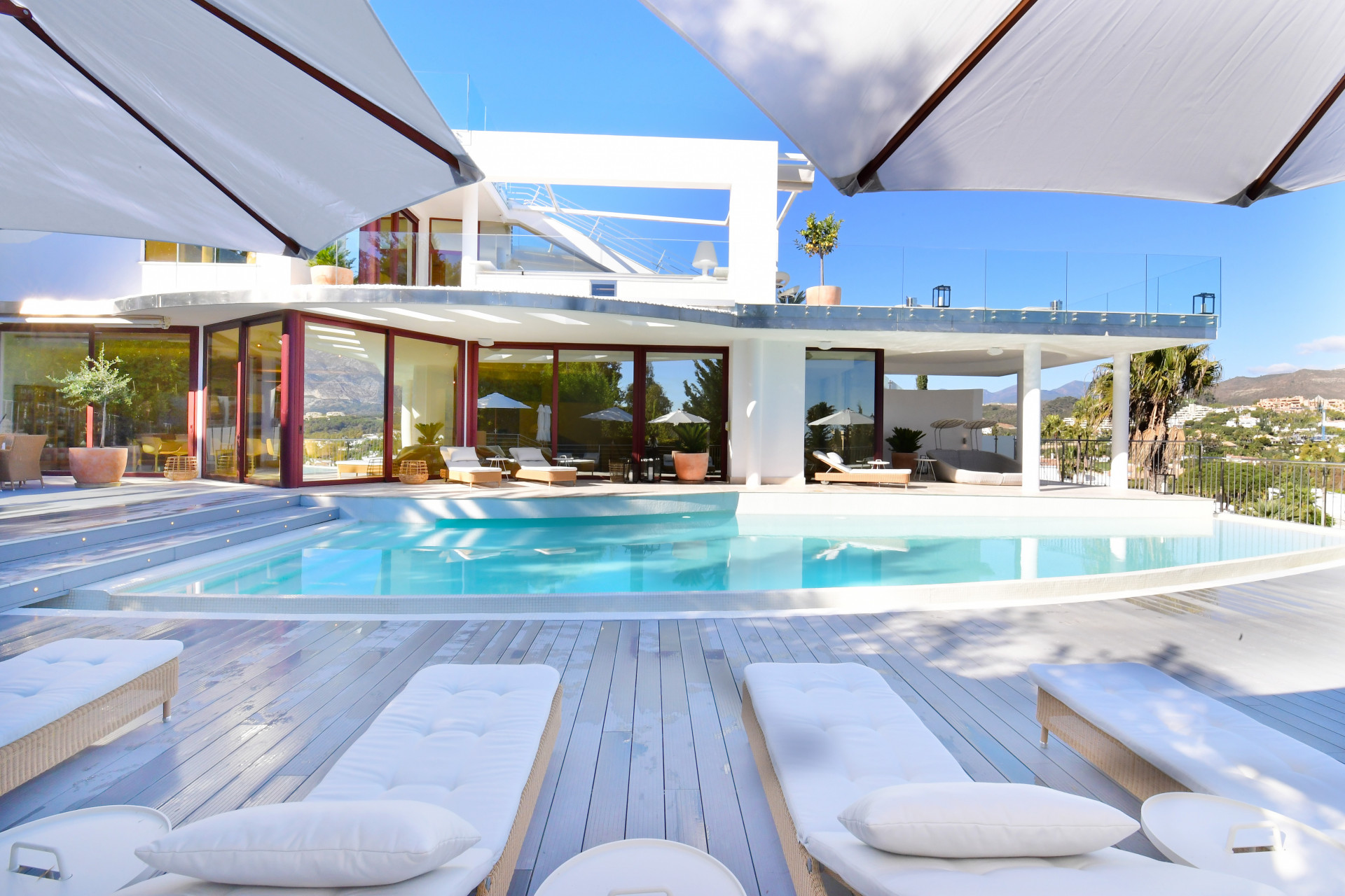 Wide angle of the pool area with lounge chairs and shaded seating under fabric canopies.