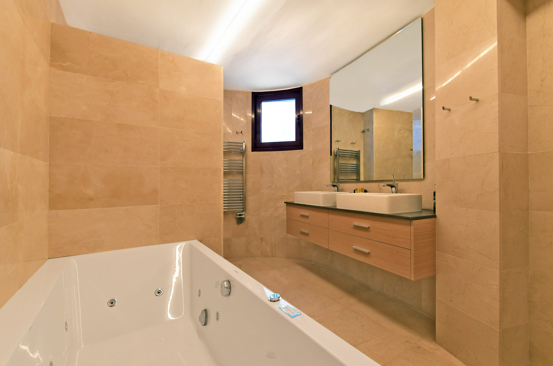 Modern bathroom featuring a jacuzzi tub, double sinks, and marble walls.
