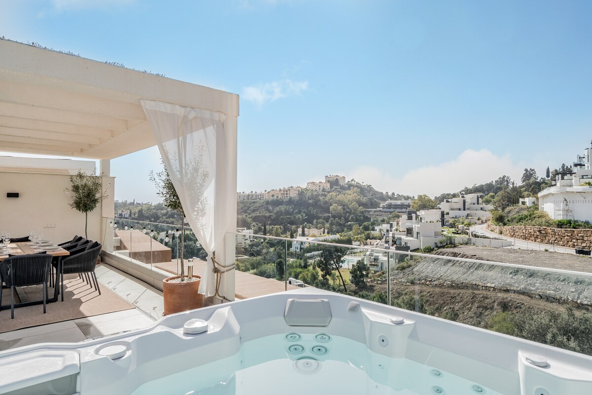 Jacuzzi on a rooftop terrace, with a dining area under a pergola and distant buildings.