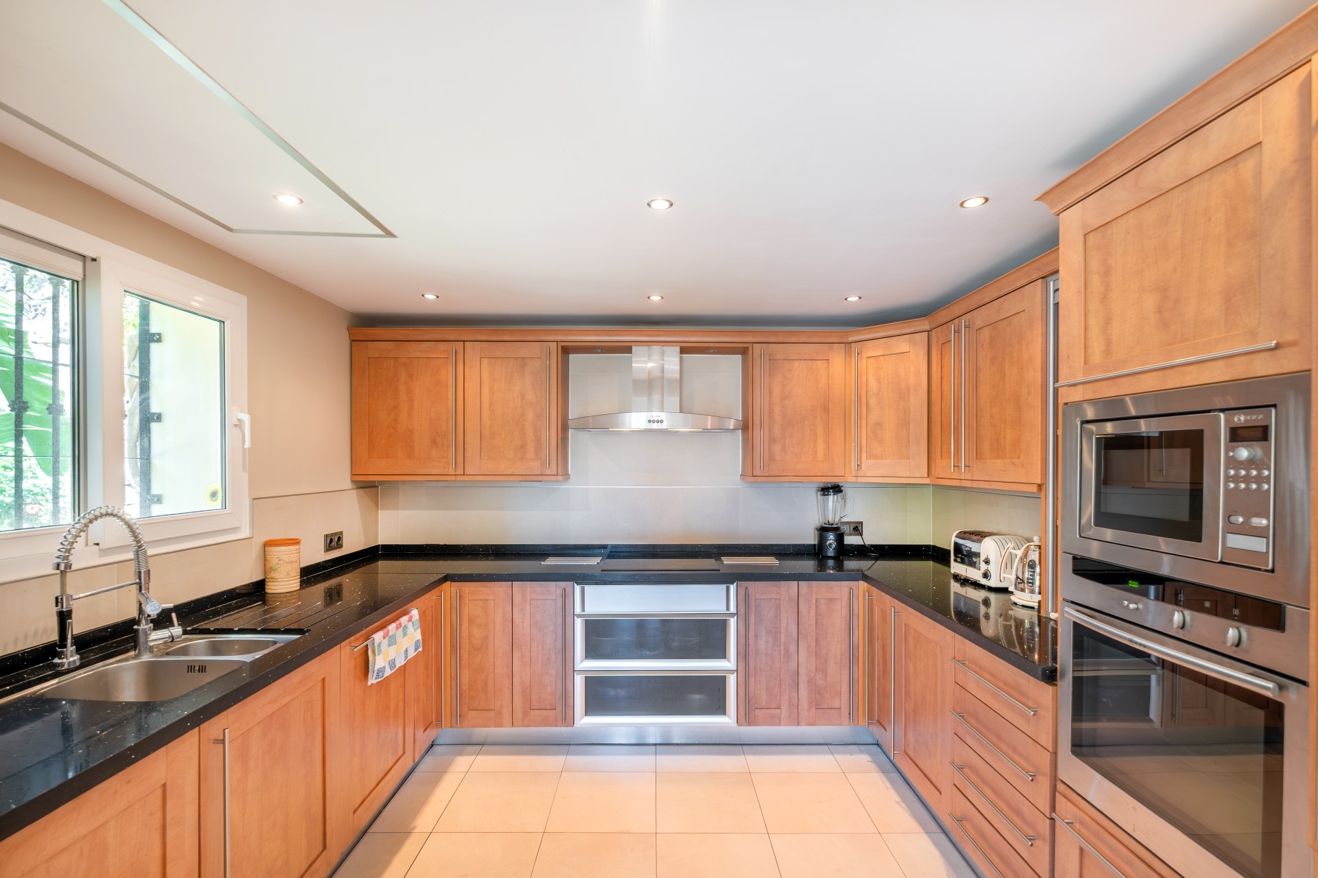 Modern kitchen with wooden cabinets, black countertops, and built-in appliances.
