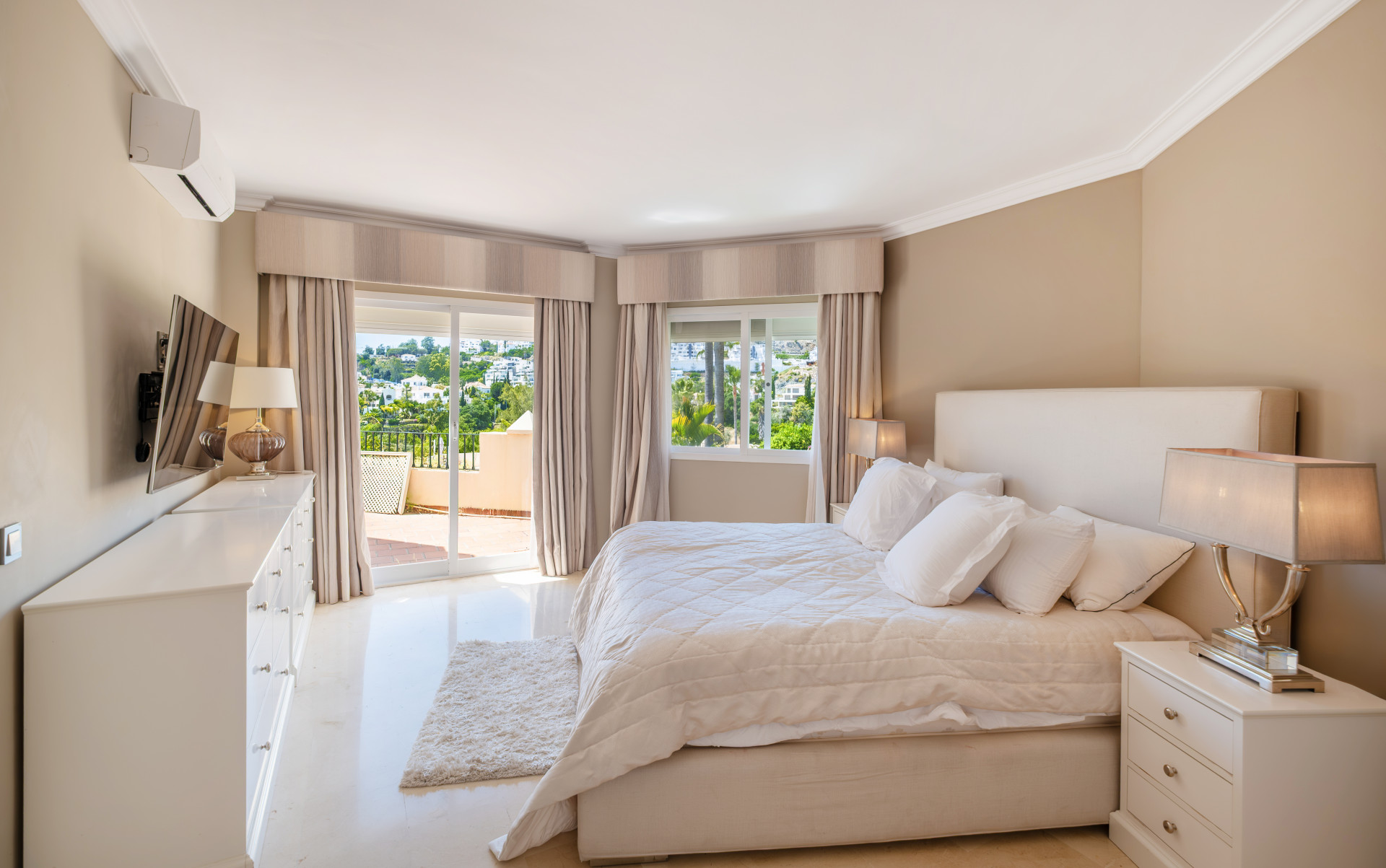 Spacious bedroom with king-size bed and balcony access, showcasing hillside views.