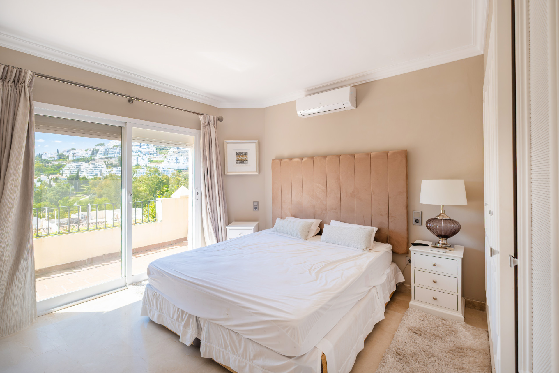 Secondary bedroom with a double bed, balcony access, and view of the surrounding hills.