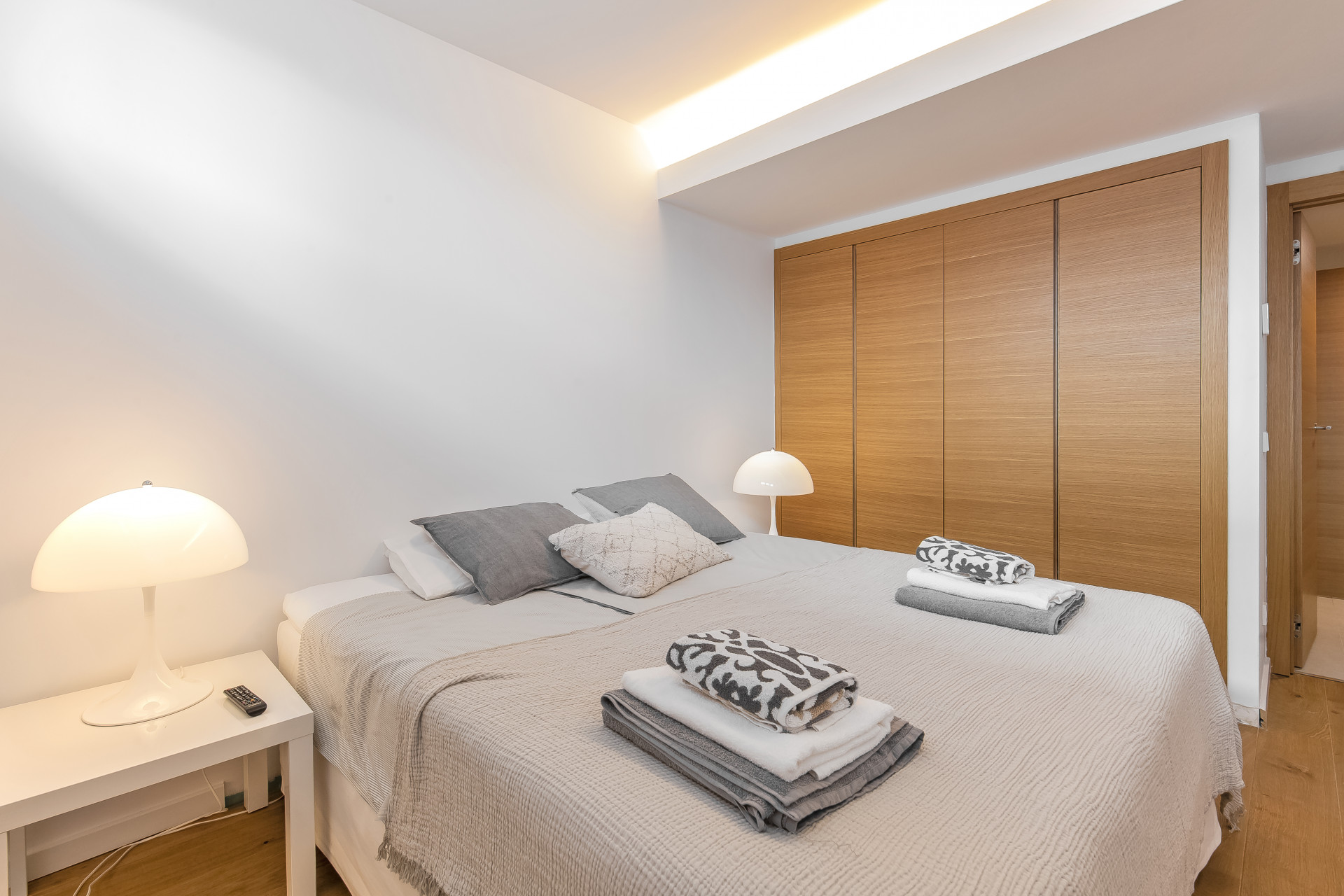 Cozy bedroom with a large bed, light-colored linens, and wooden cabinetry.