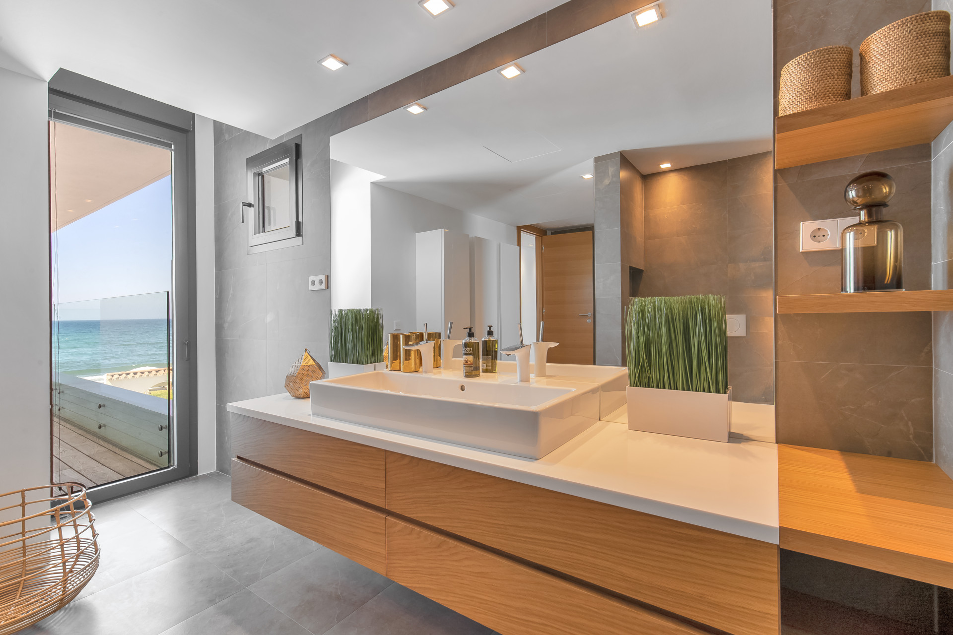Modern bathroom with ocean view, wooden vanity, and large mirror.