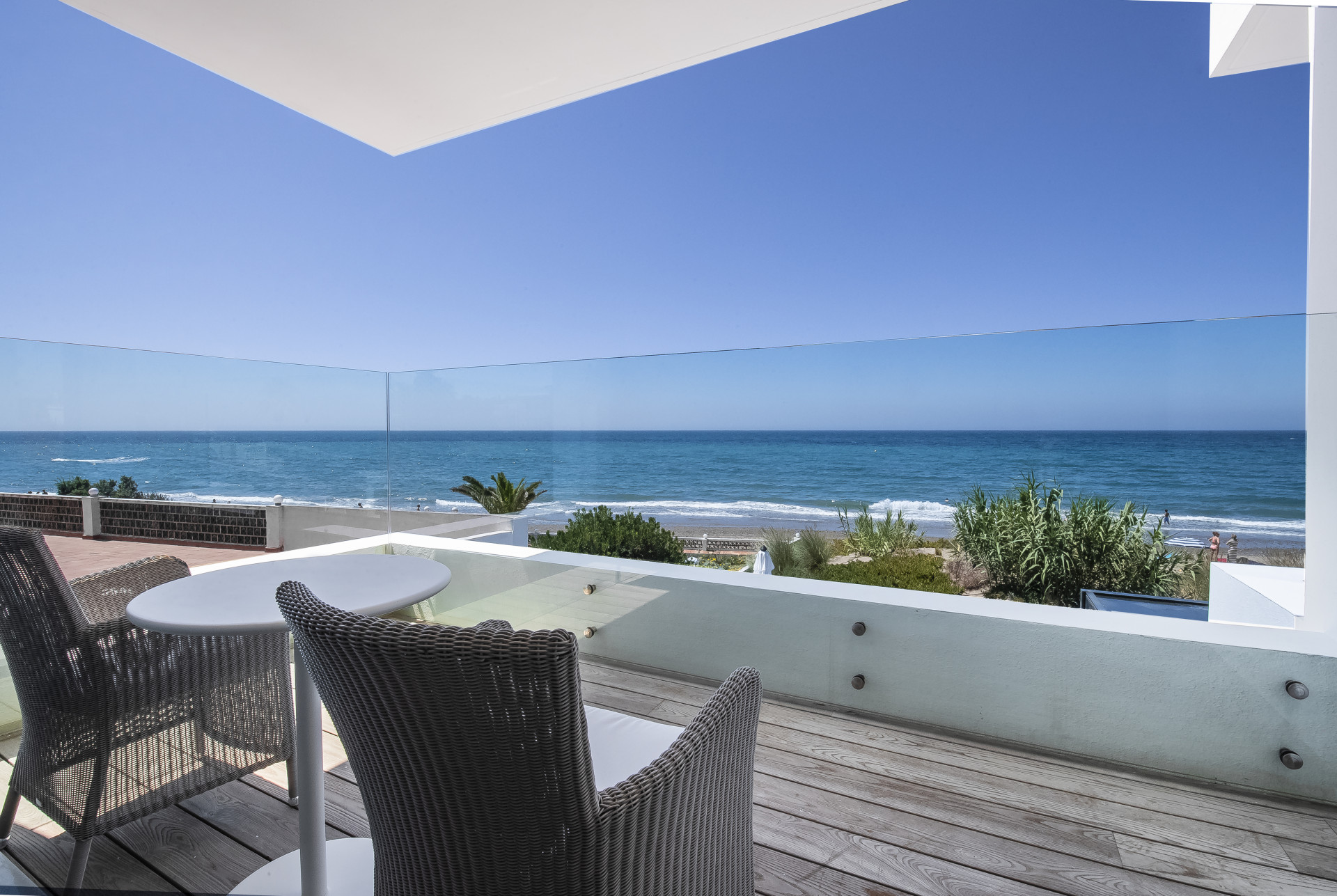 Balcony view showcasing outdoor seating and beachfront scenery.