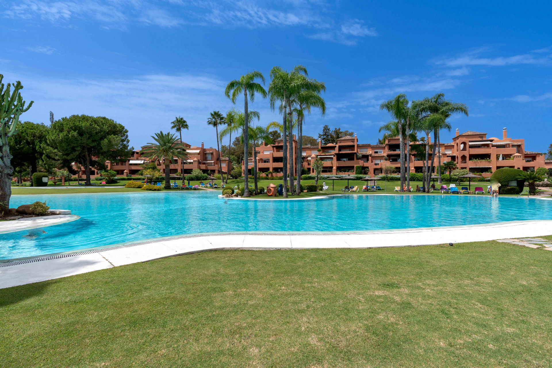 Elegant 3-bedroom first-floor apartment in prestigious Guadalmina Baja, just minutes from the beach. Spacious interiors, 55 m² terrace, stunning gardens, and lagoon-style pool in a secure community.