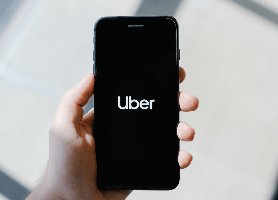 Fotografía de alguien sosteniendo un teléfono con la pantalla de carga de la App Uber Car-ride 