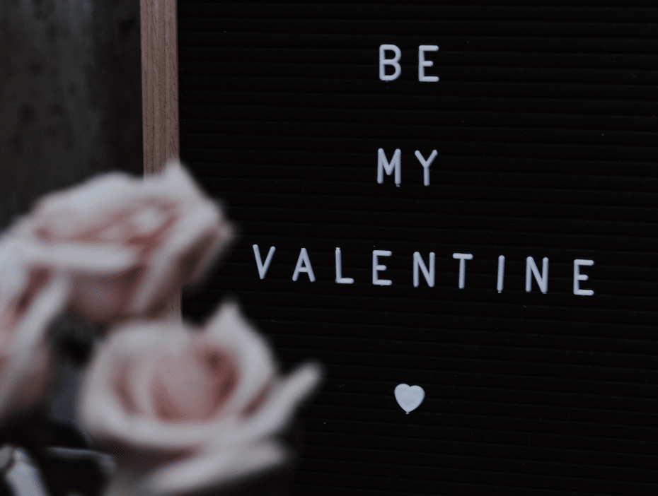 Foto van een bord met de tekst "Be My Valentine" met enkele roze rozen
