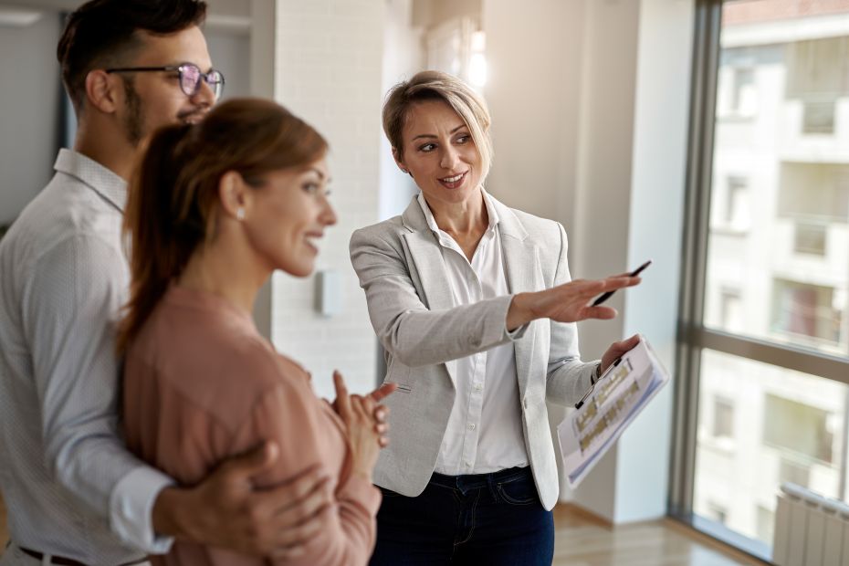 Sonriente agente inmobiliario hablando con una pareja interesada en comprar una nueva casa.