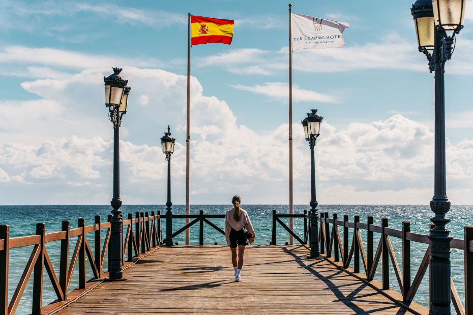 Photo d'une femme marchant sur la jetée du Marbella Club à côté du Puente Romano à Marbella. 