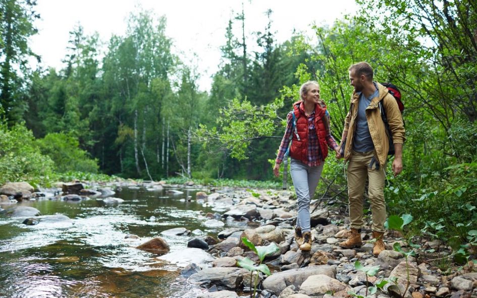 Couple walking along river in pine forest like around Istan