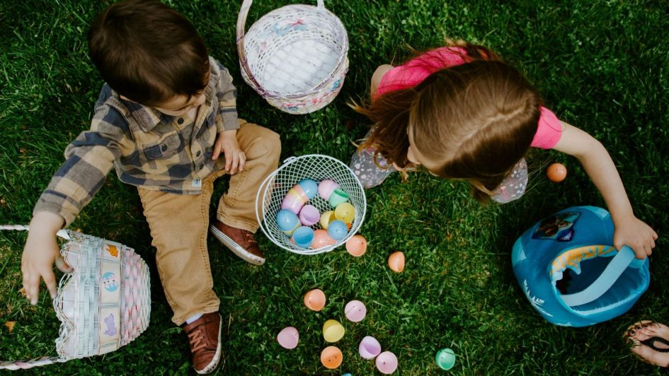 Children on grass with coloured Easter eggs.