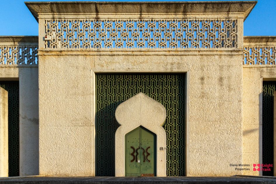 Impresionante puerta arqueada con intrincados patrones geométricos en una elegante fachada texturizada.